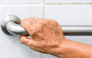 Elderly person's hand holding bathroom railing