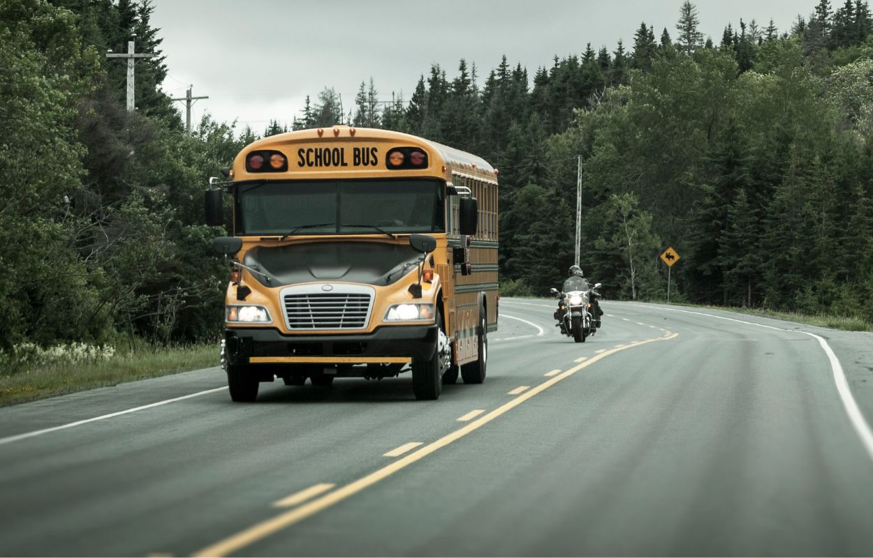 School bus with motorcycle approaching behind