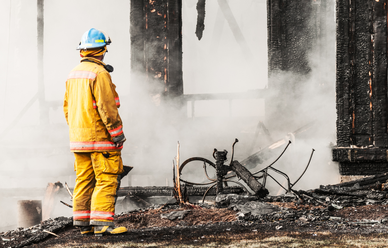 Fire investigator standing amidst the smoking remnants of a building fire.